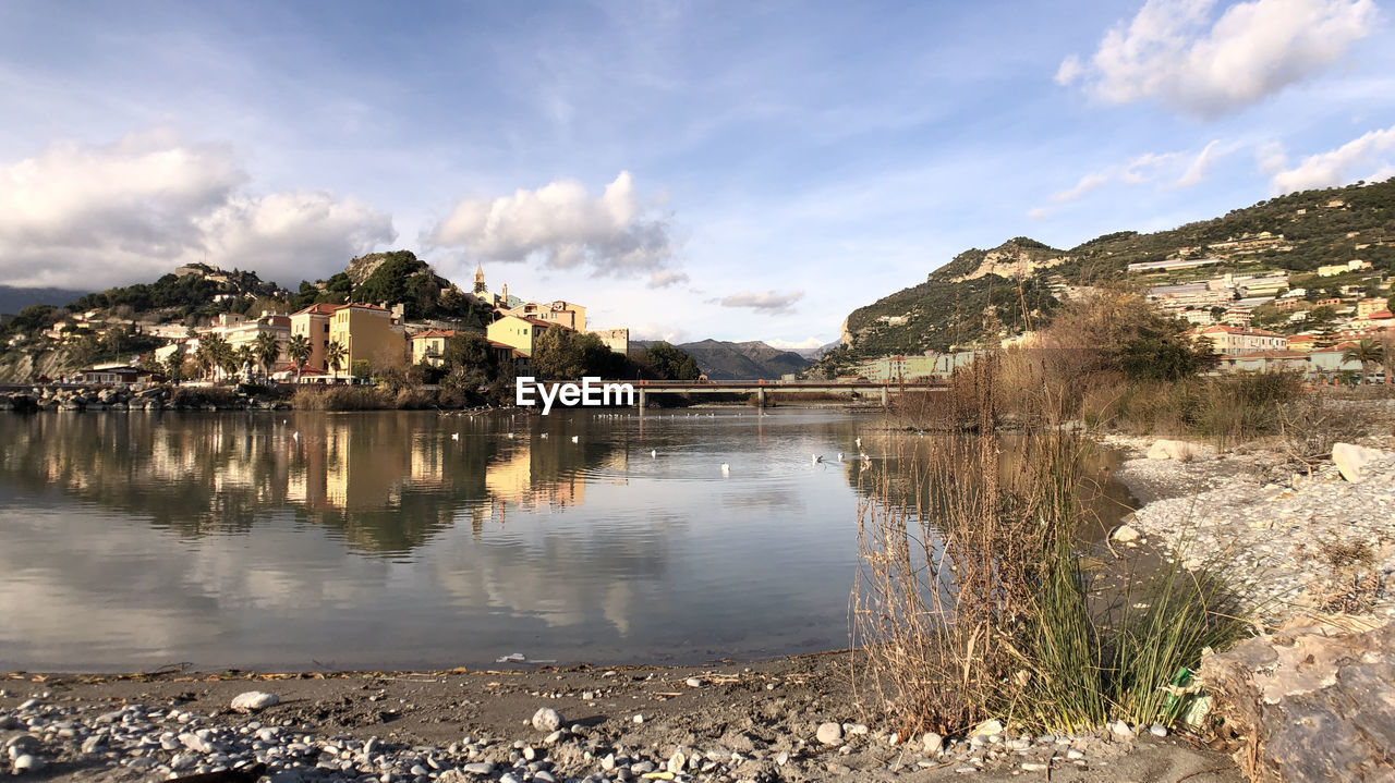 Scenic view of lake by buildings against sky