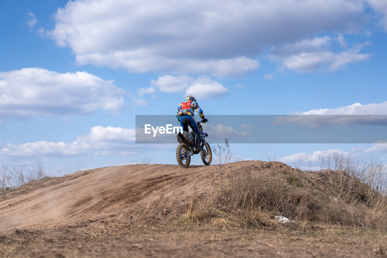 MAN RIDING MOTORCYCLE ON LAND