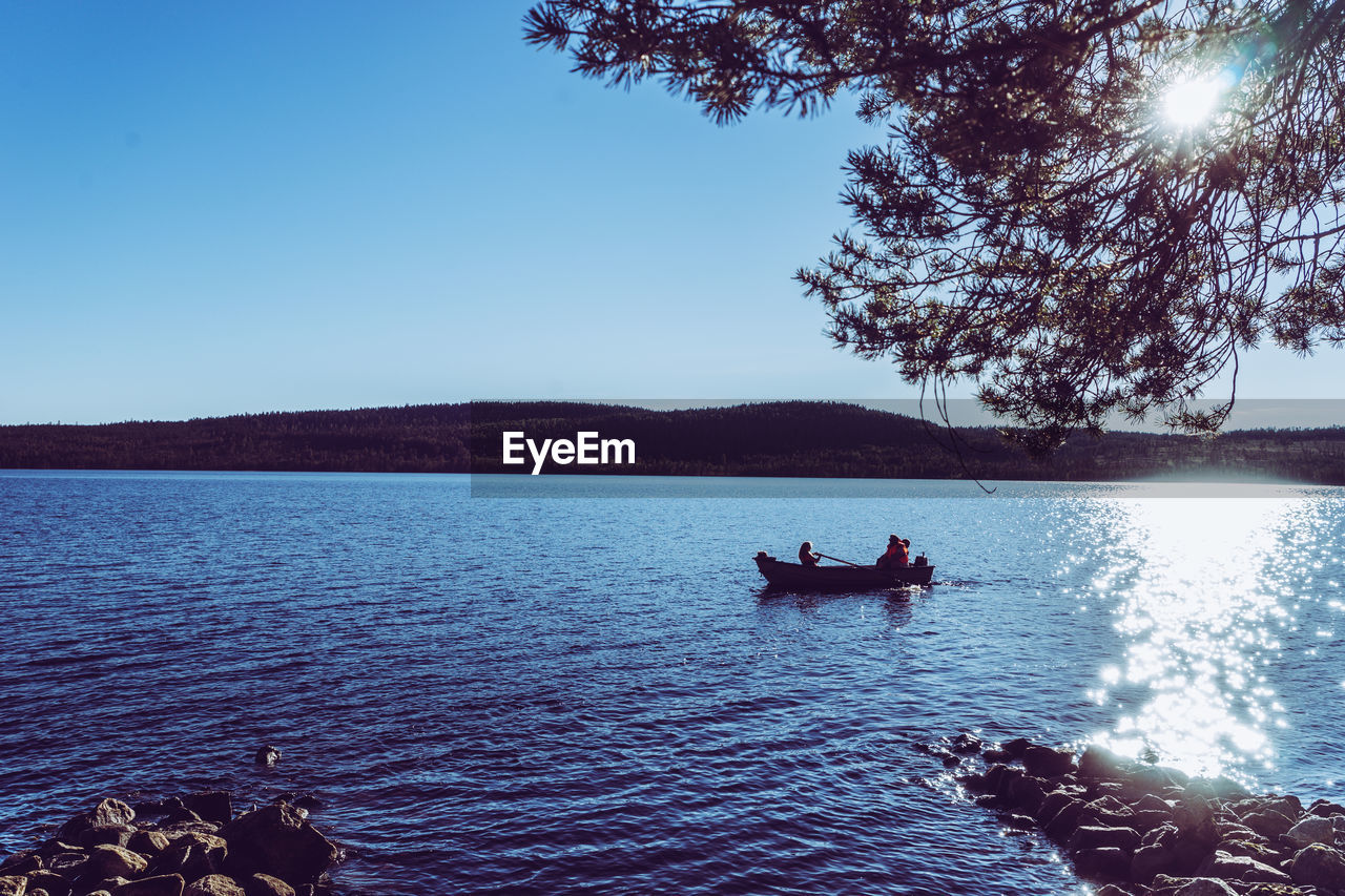 People on boat against clear sky