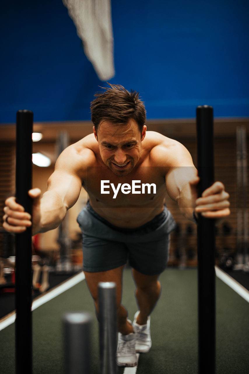 Shirtless man exercising in gym