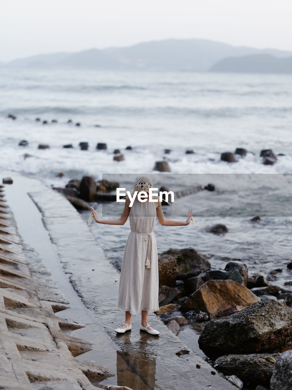 rear view of woman walking on beach against sky during sunset