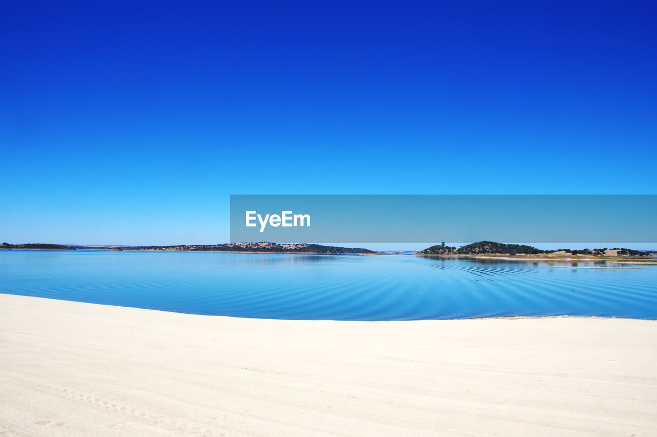 Scenic view of beach against clear blue sky