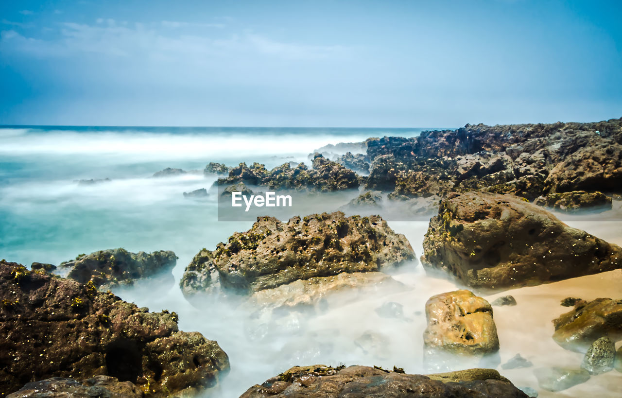 Scenic view of rocks on beach against sky