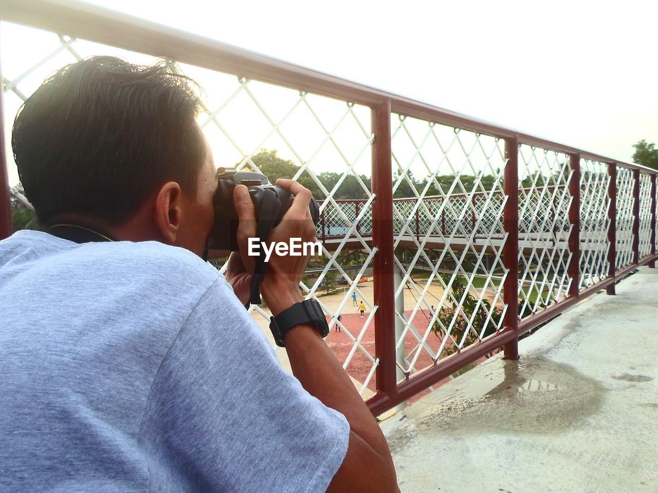 Side view of man photographing by railing