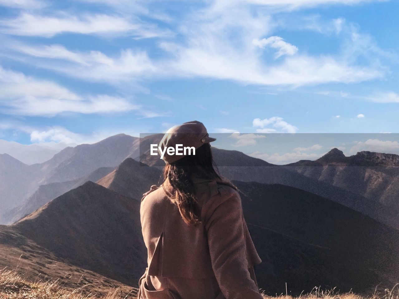 Rear view of woman looking at mountain range against sky