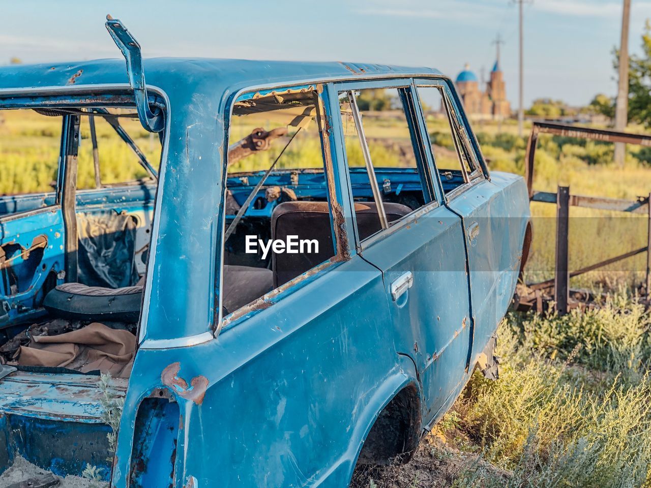 Abandoned car on land against sky