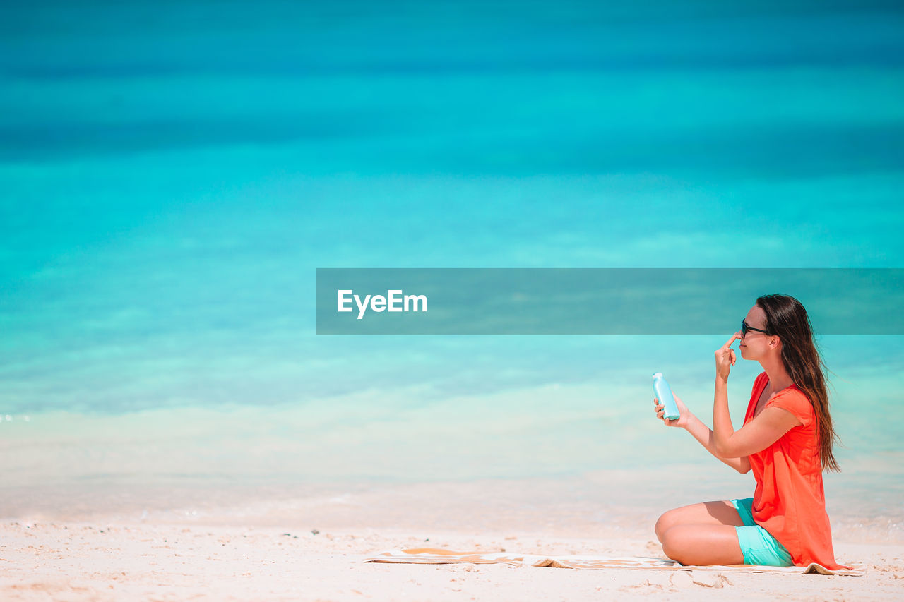 WOMAN SITTING AT BEACH