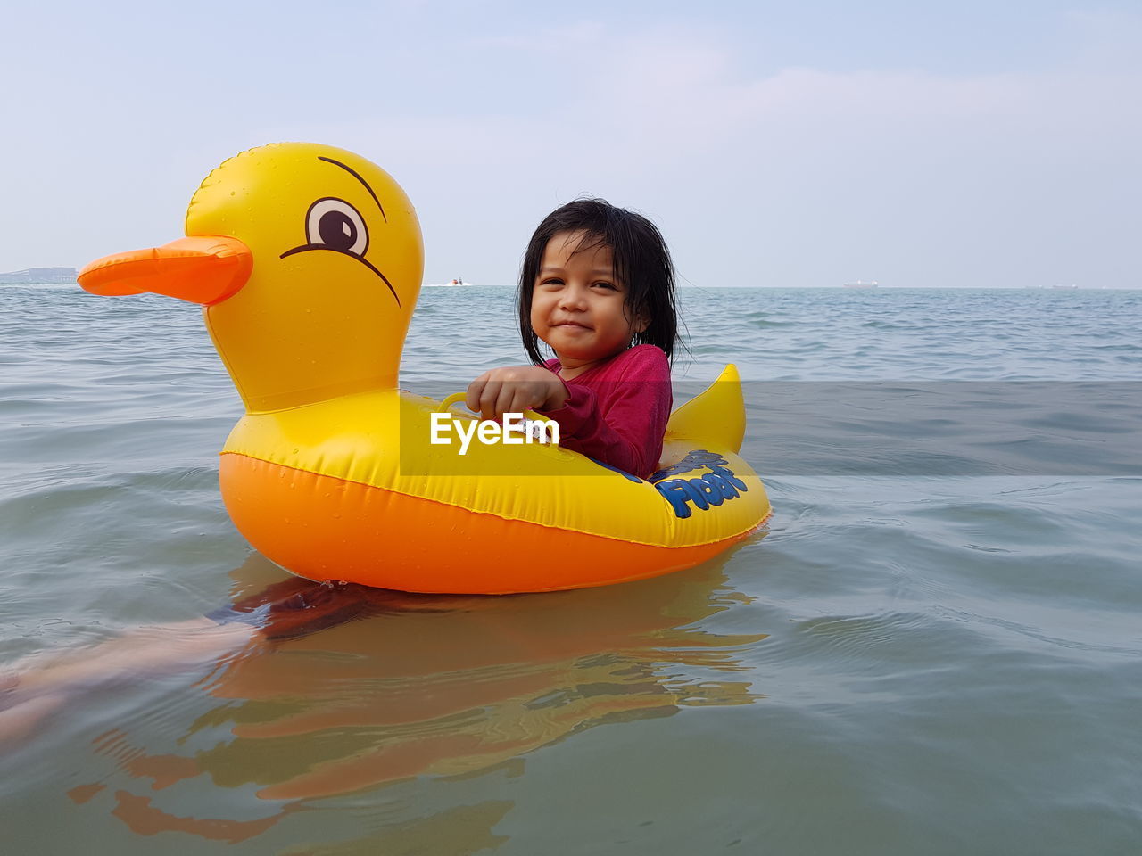 PORTRAIT OF HAPPY BOY PLAYING WITH TOY IN SEA