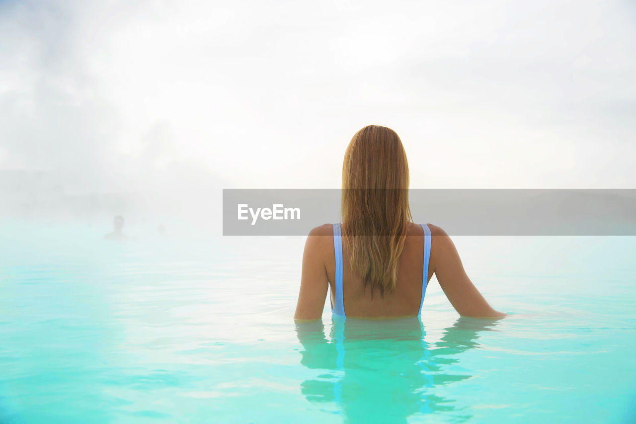 Rear view of woman in hot spring during foggy weather