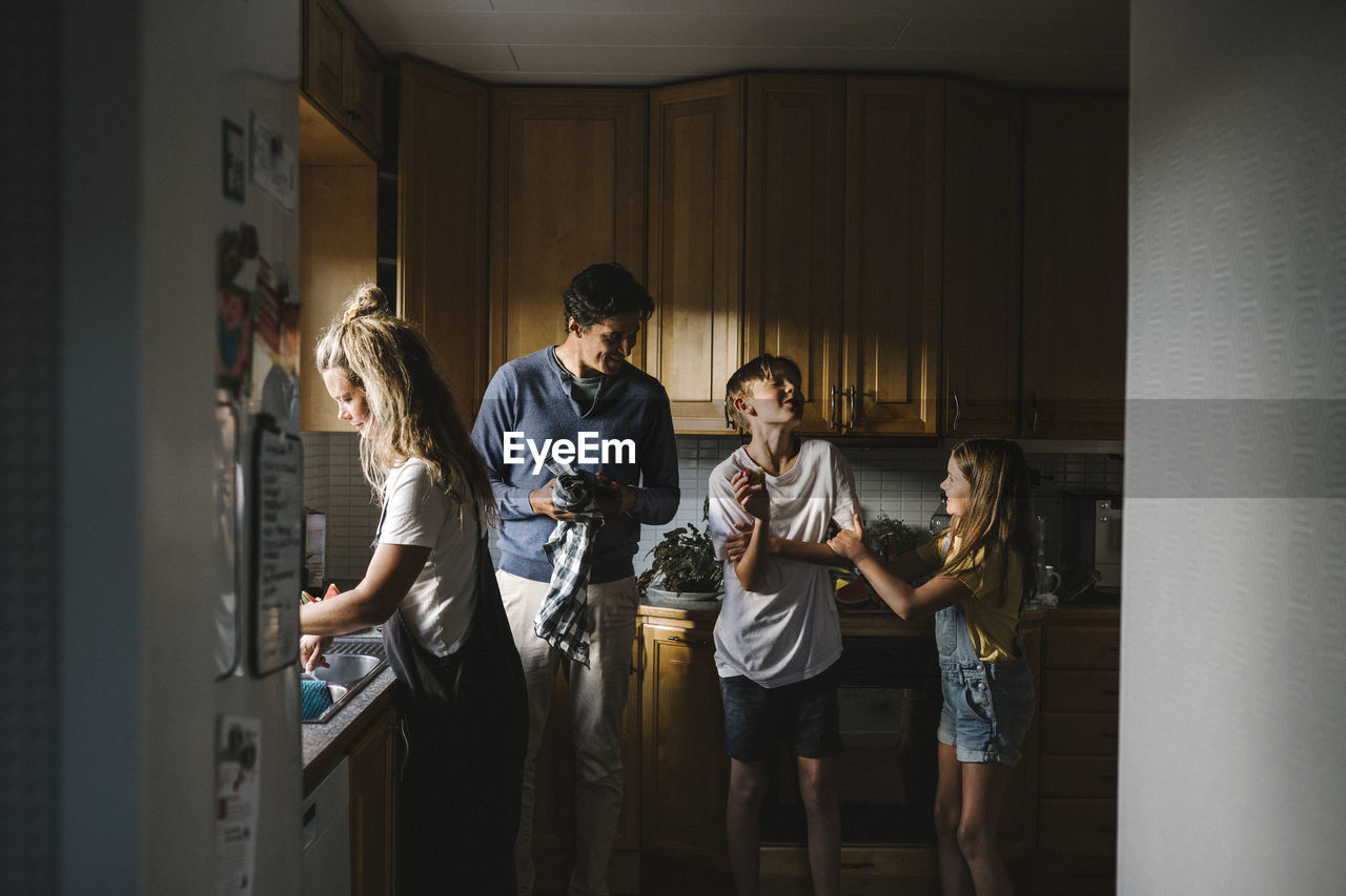 Siblings with parents standing in kitchen