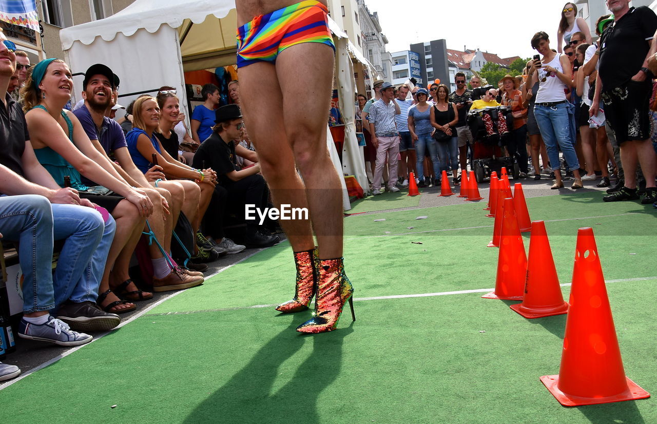 Low section of genderblend man wearing high heels standing in city