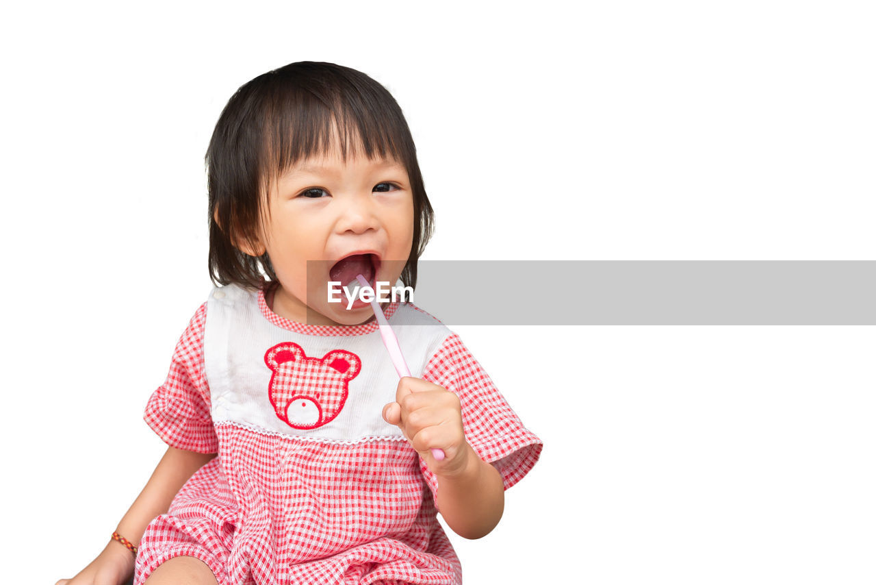 Portrait of cute girl brushing teeth over white background