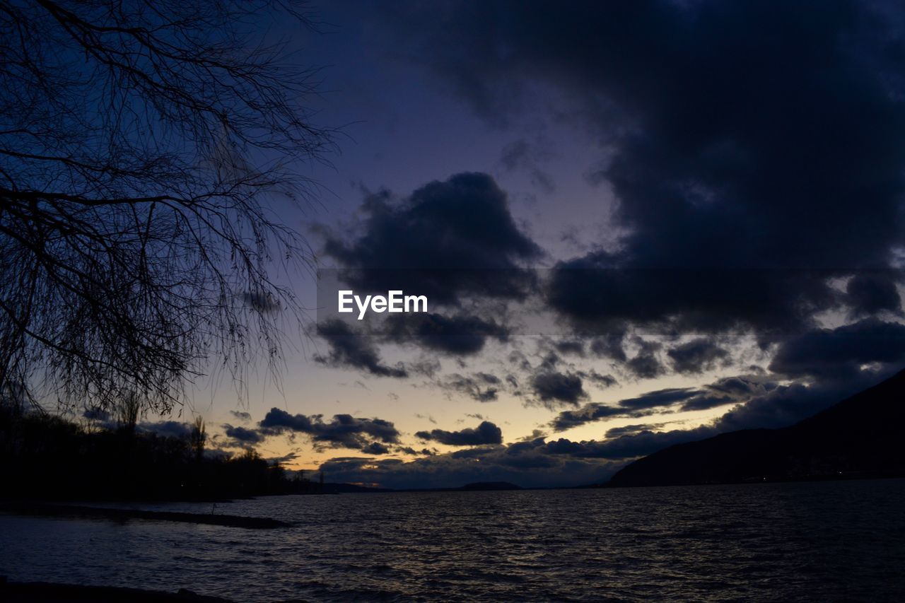 SCENIC VIEW OF SEA BY SILHOUETTE MOUNTAIN AGAINST SKY