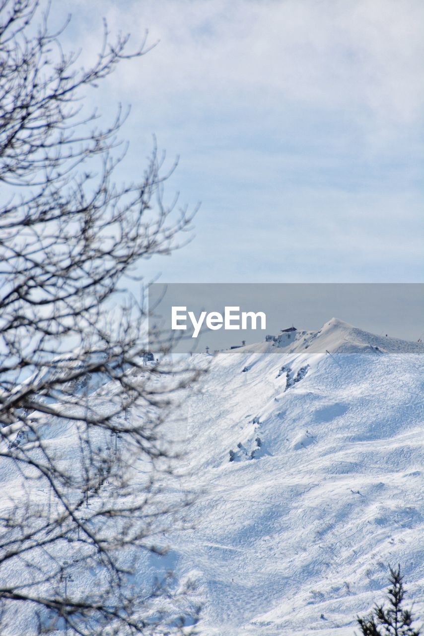 Scenic view of snow covered mountains against cloudy sky