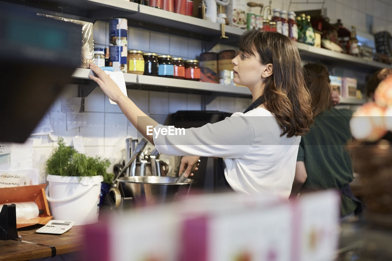 Female owner arranging food products on shelf in store