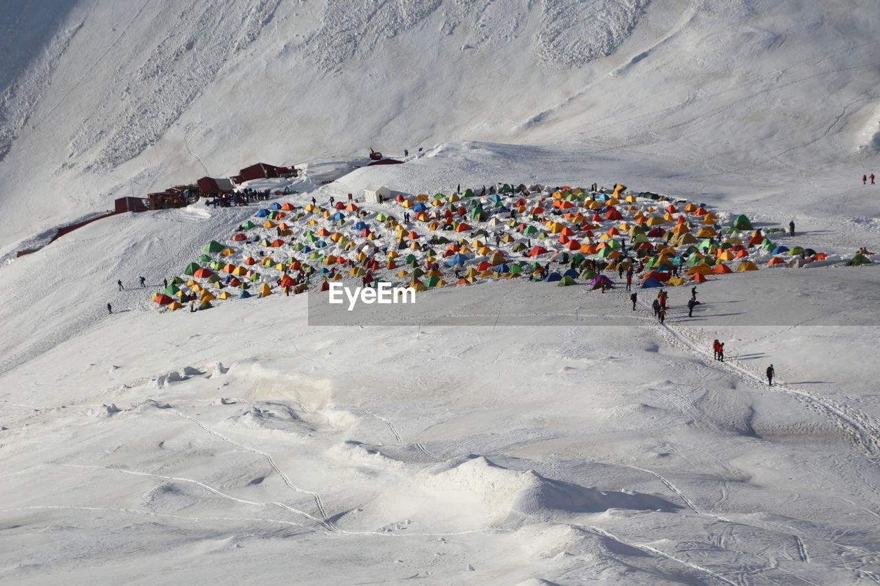 High angle view of colorful tents by snowcapped mountain