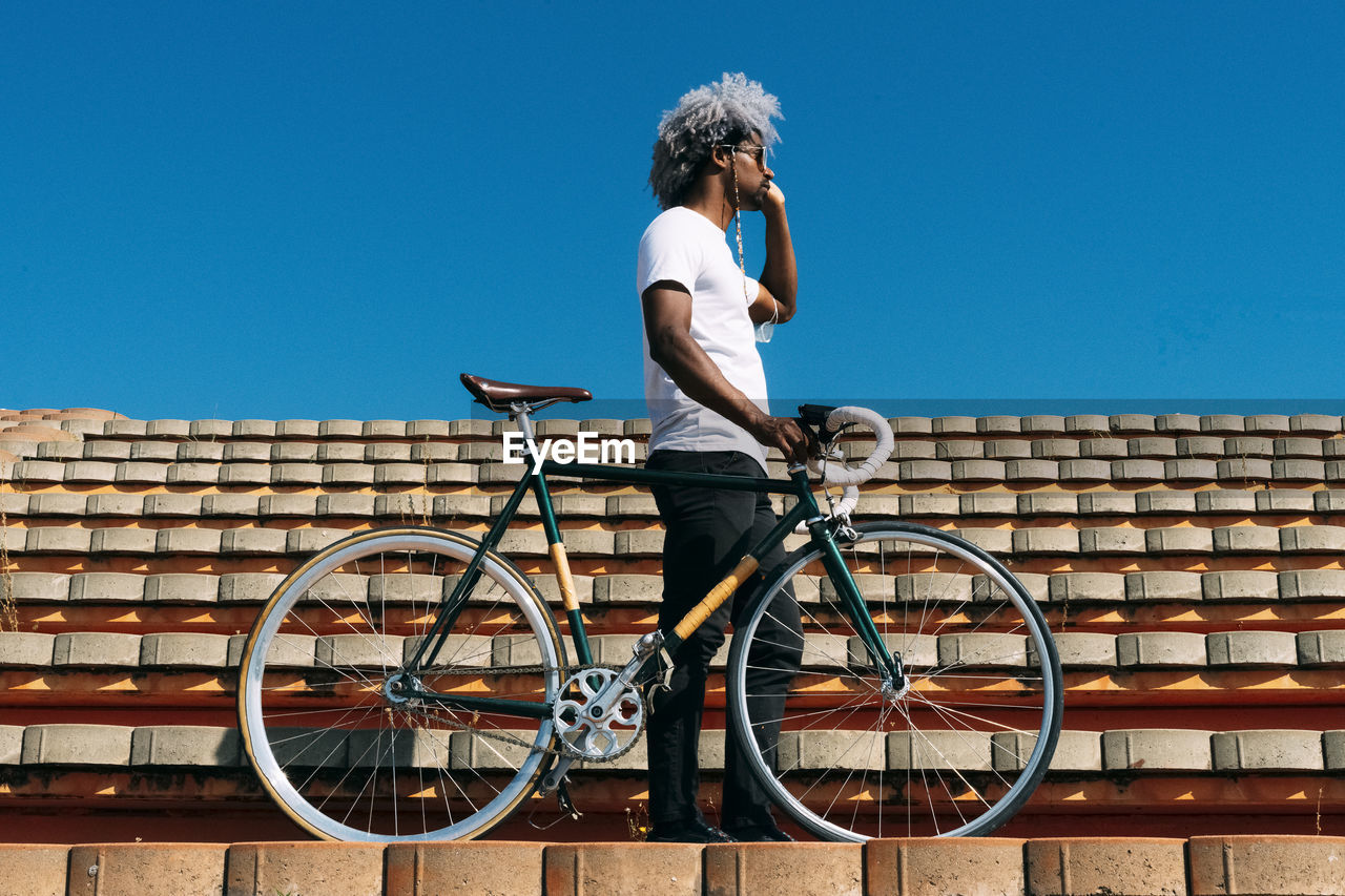 Afro and black man carrying the bike on some stairs. black rider concept. cycling in the city.