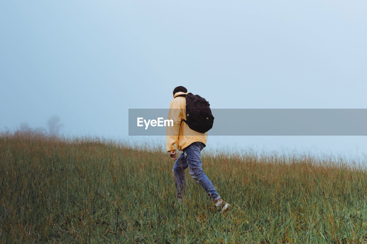 Man walking on field against clear sky