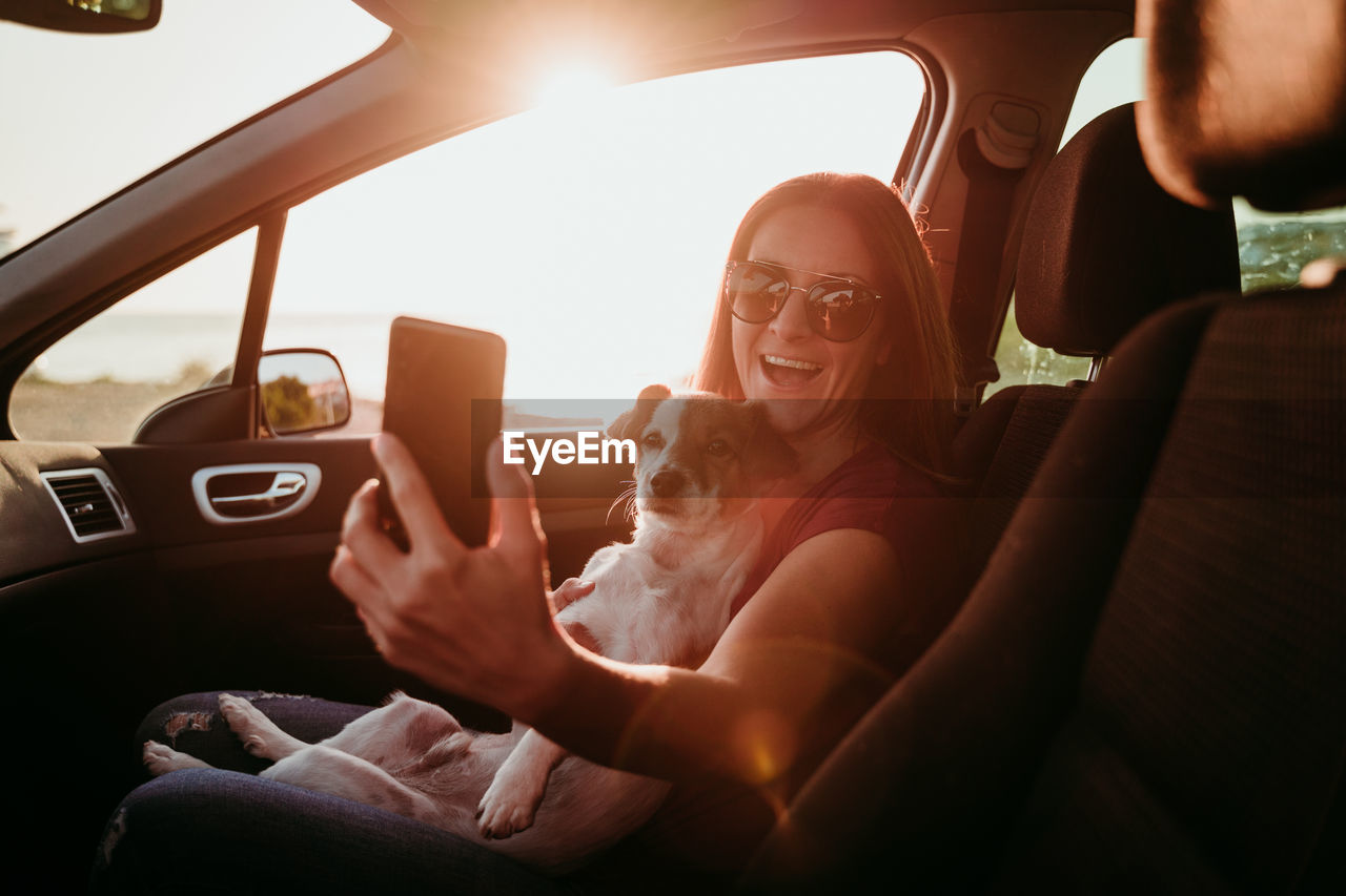 Woman with dog sitting in car