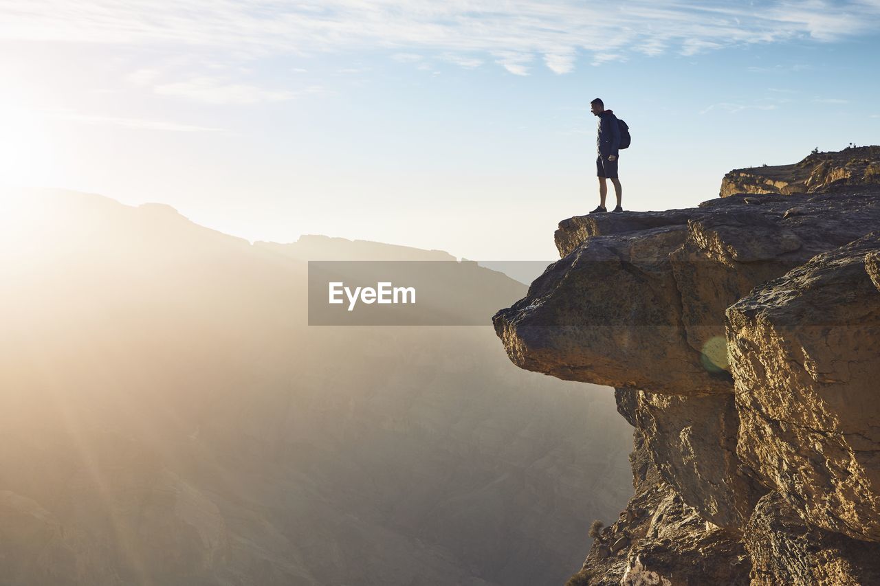 Man standing on rock formation against sky