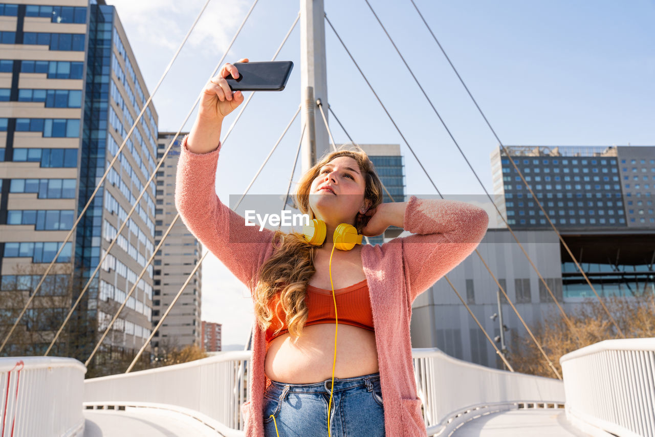 Young woman taking selfie on footbridge