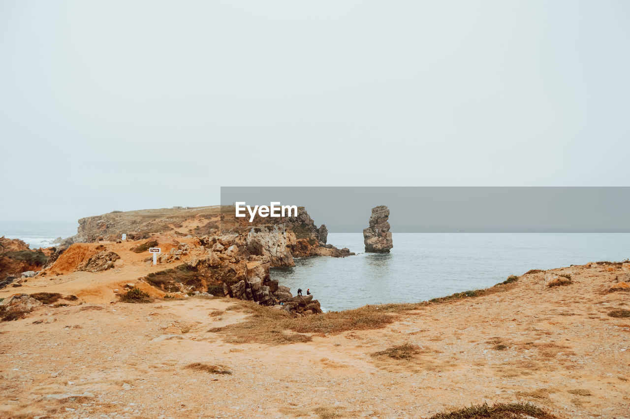 Rock formations on shore against clear sky