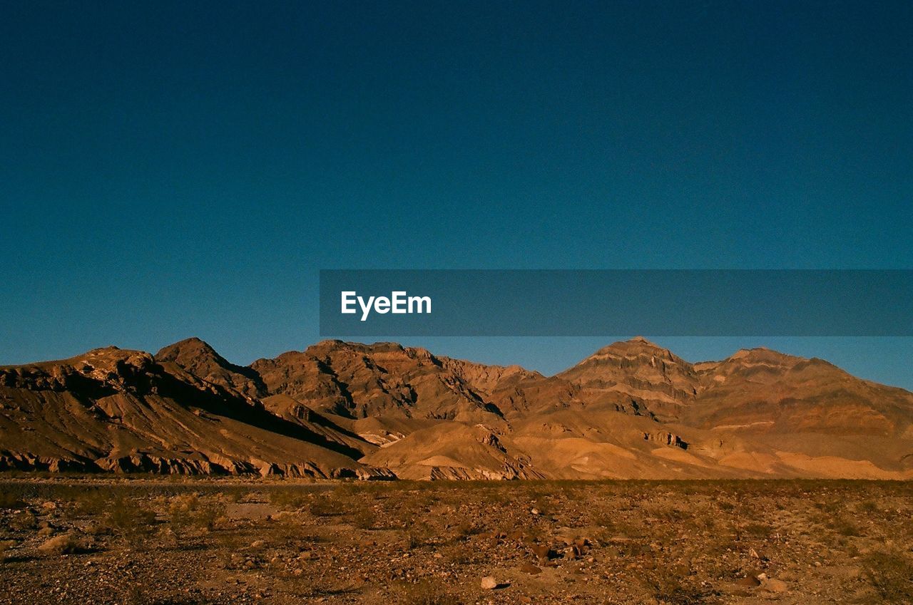 Scenic view of landscape and mountains against clear blue sky