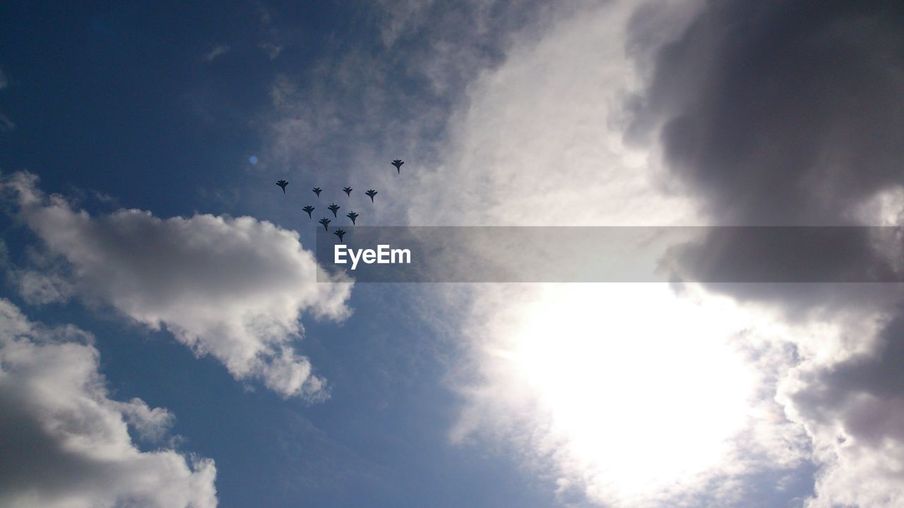 Low angle view of silhouette airplanes flying against sky