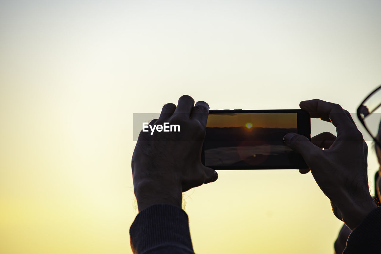 MAN PHOTOGRAPHING AT SUNSET