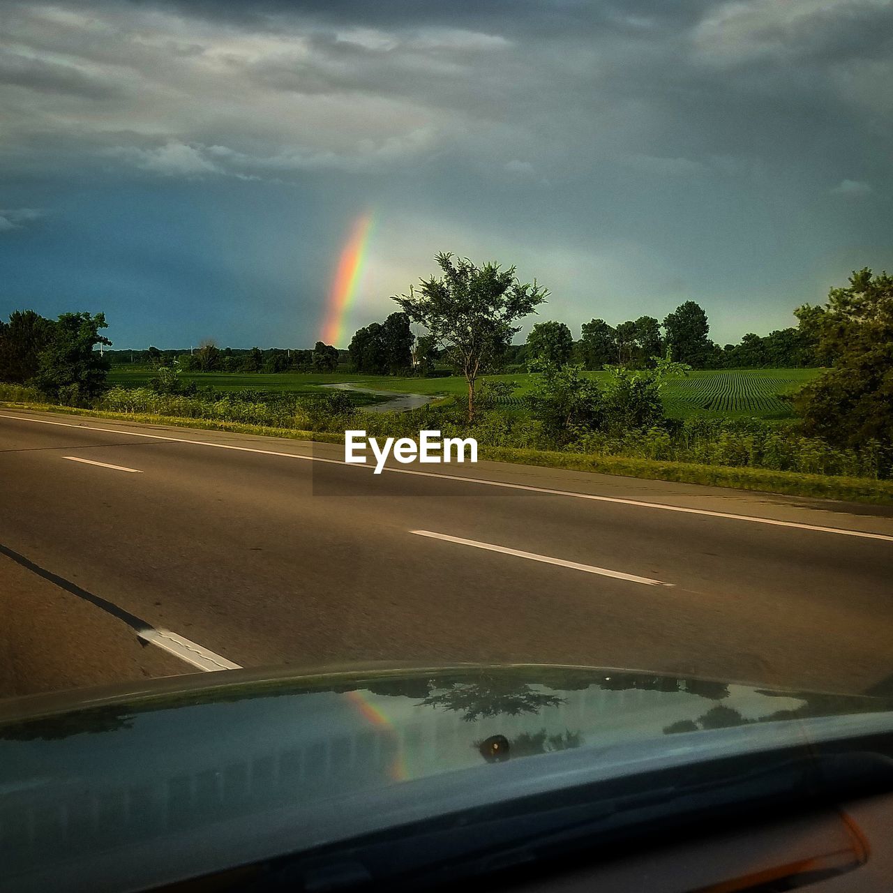 RAINBOW OVER ROAD SEEN THROUGH WINDSHIELD