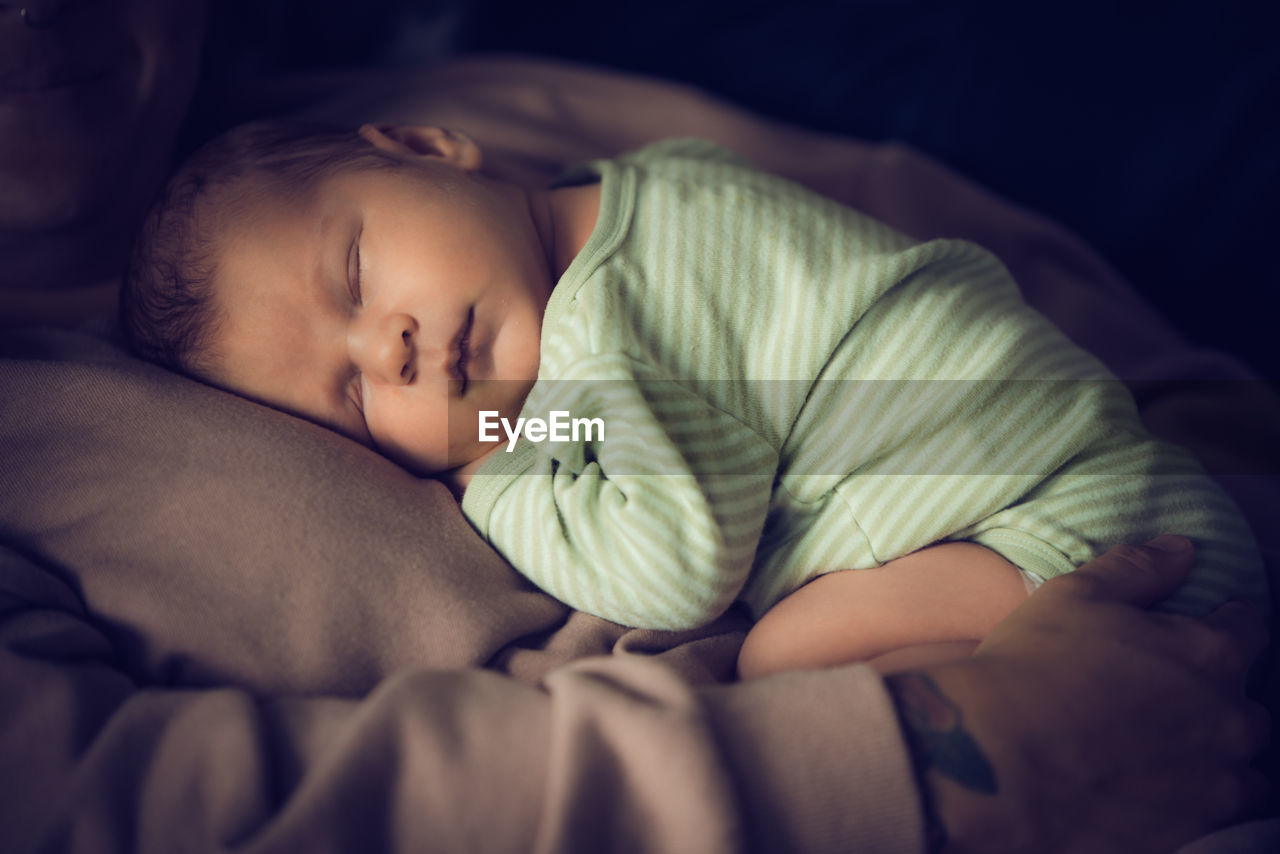 Close-up of cute baby boy sleeping on bed