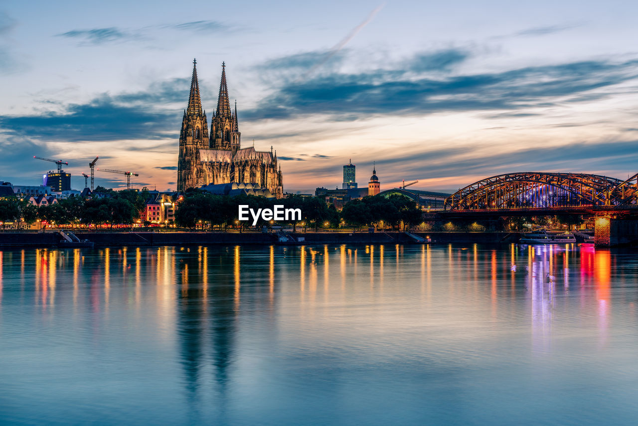 Panoramic view of cologne cathedral with hohenzollern bridge at nightfall, germany.