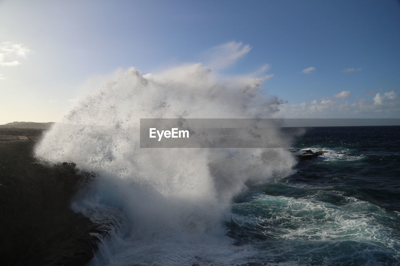 Waves splashing on sea against sky