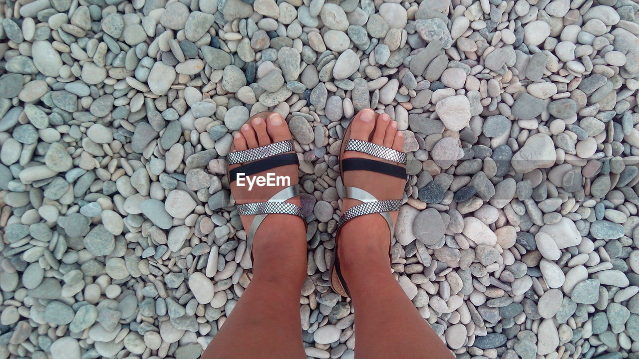 Low section of woman standing on pebbles