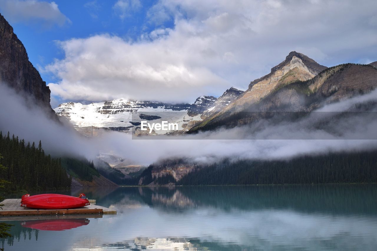 Boat moored at river against snowcapped mountains