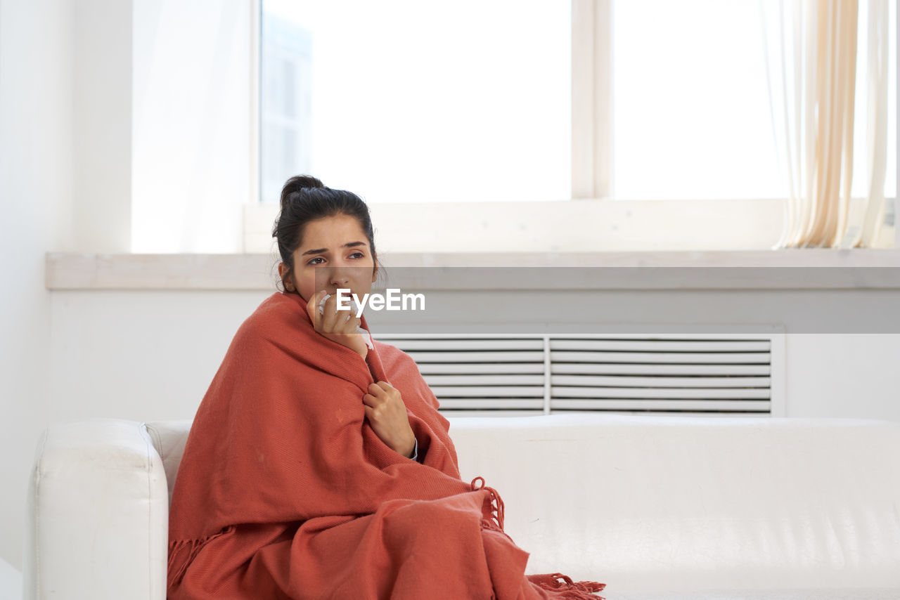 Ill woman looking away while sitting at home