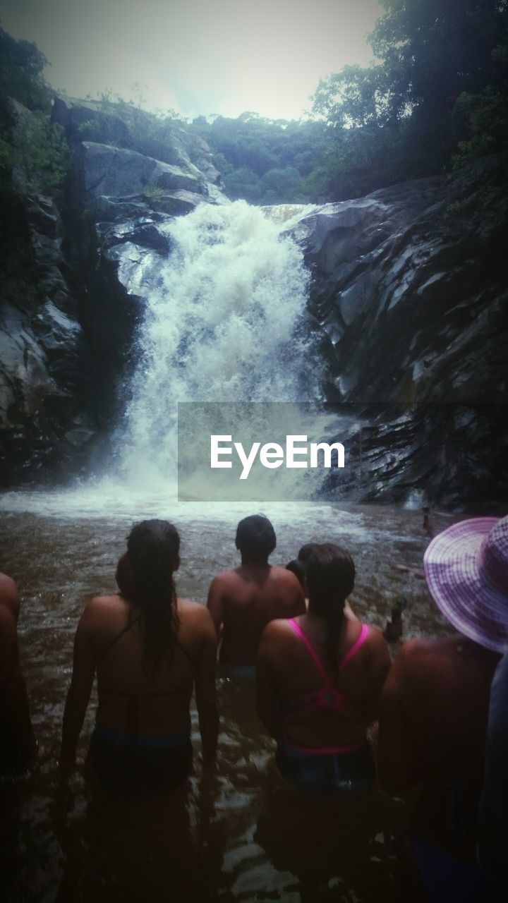 People enjoying waterfall in forest