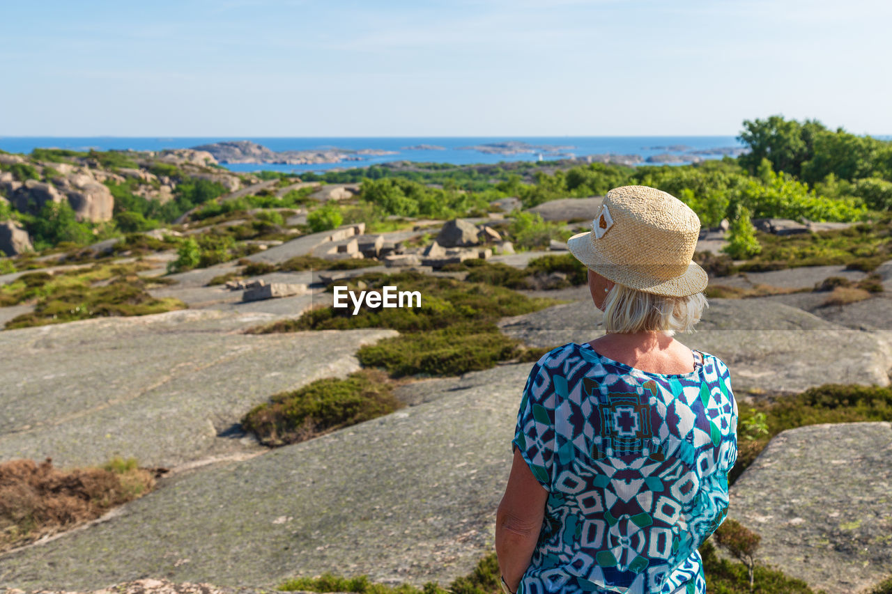 Rear view of senior woman looking at sea against sky