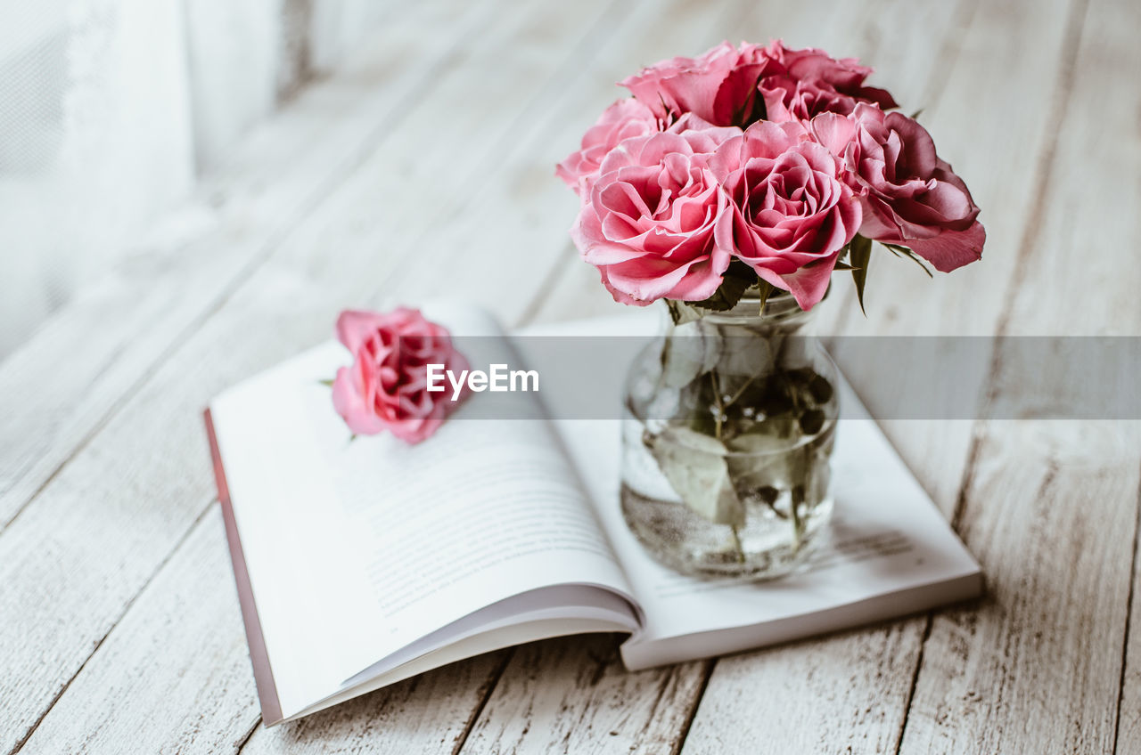 Close-up of roses in vaseon book at table