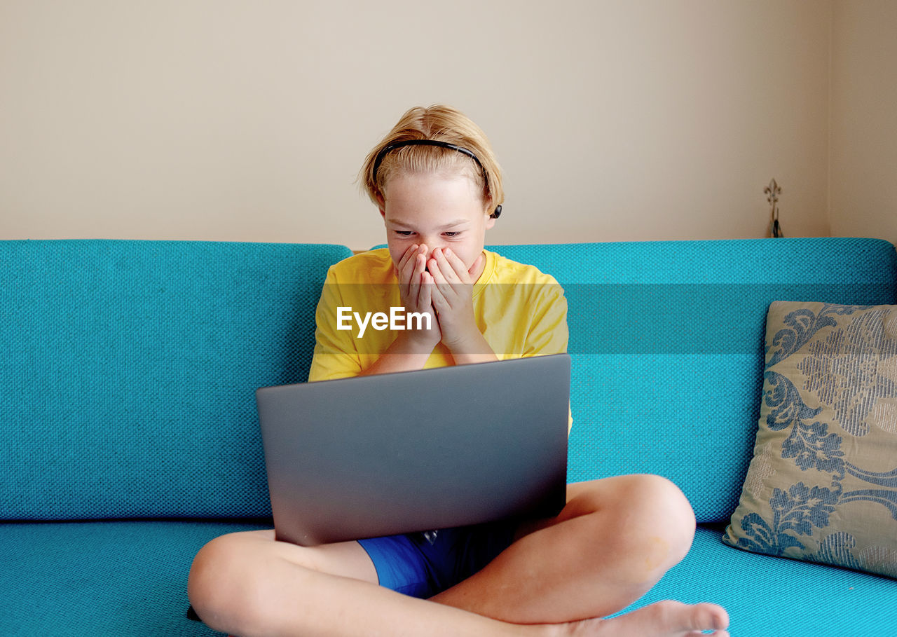 Boy using laptop while sitting on sofa at home