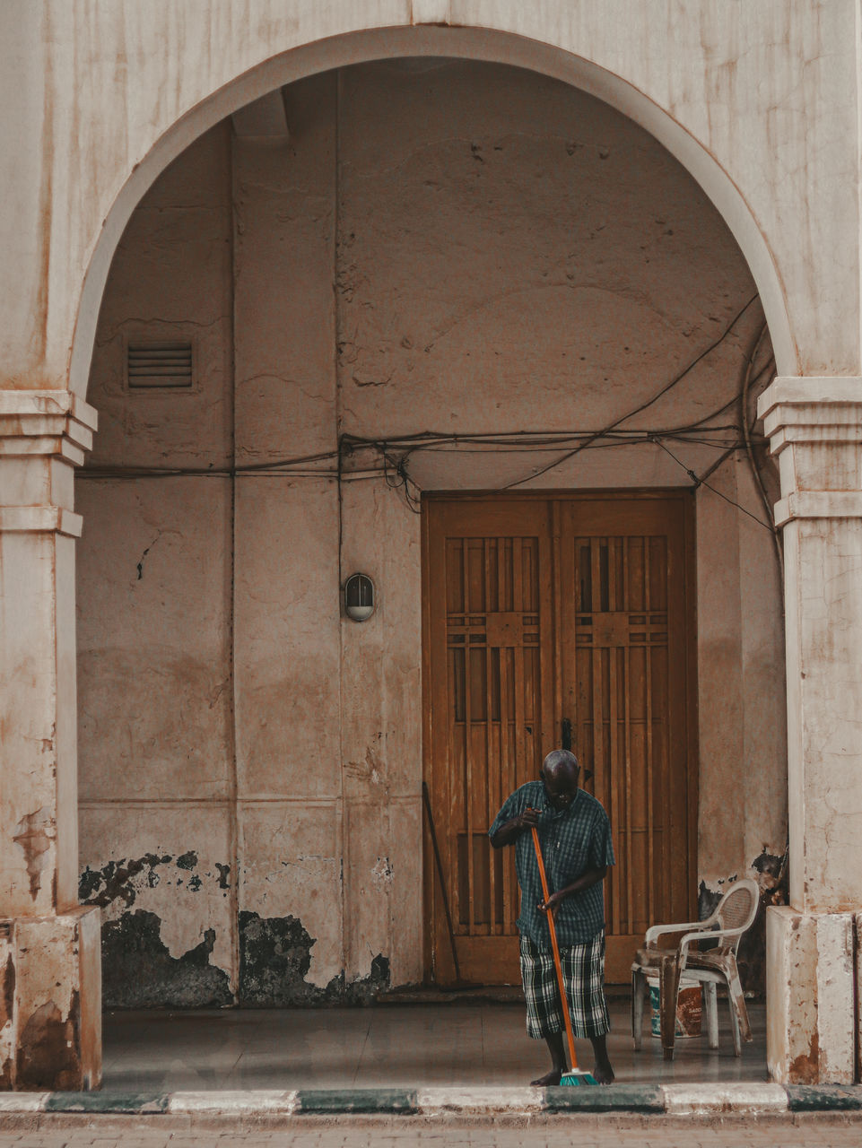 Rear view of man sweep the corridor of an ancient building 