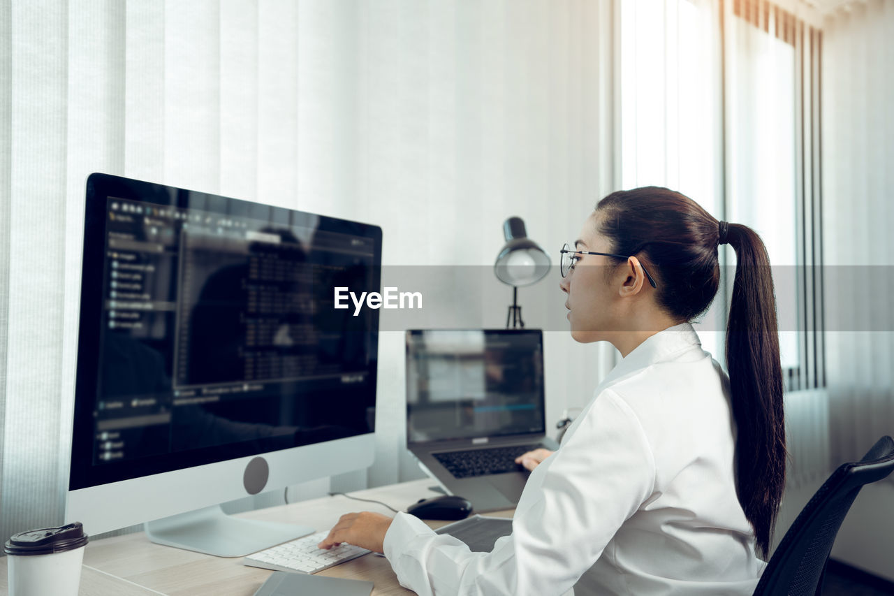 Side view of young woman working on computer in office