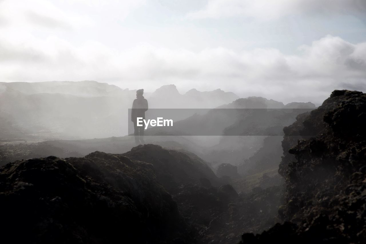 Person standing on mountain against sky