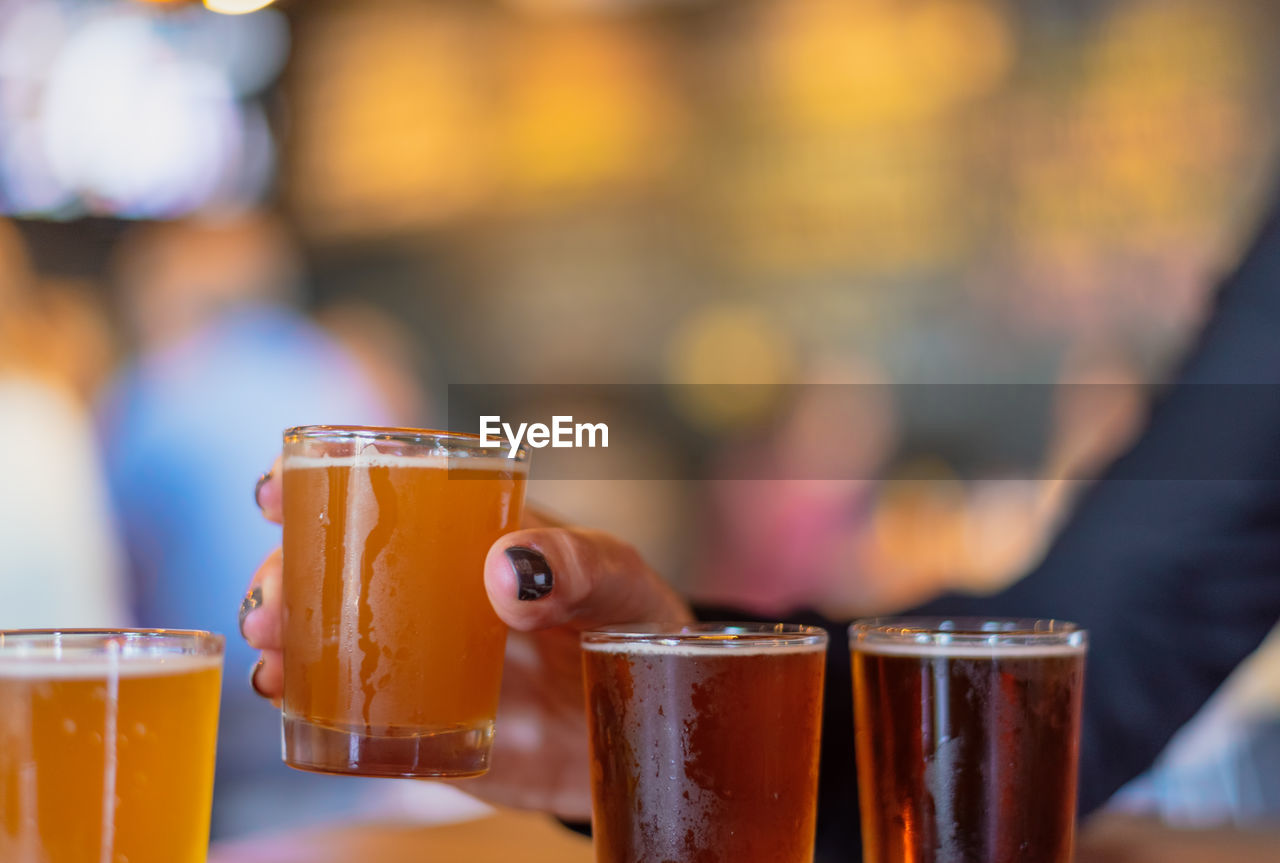 Close-up of woman reaching for beer glass on table