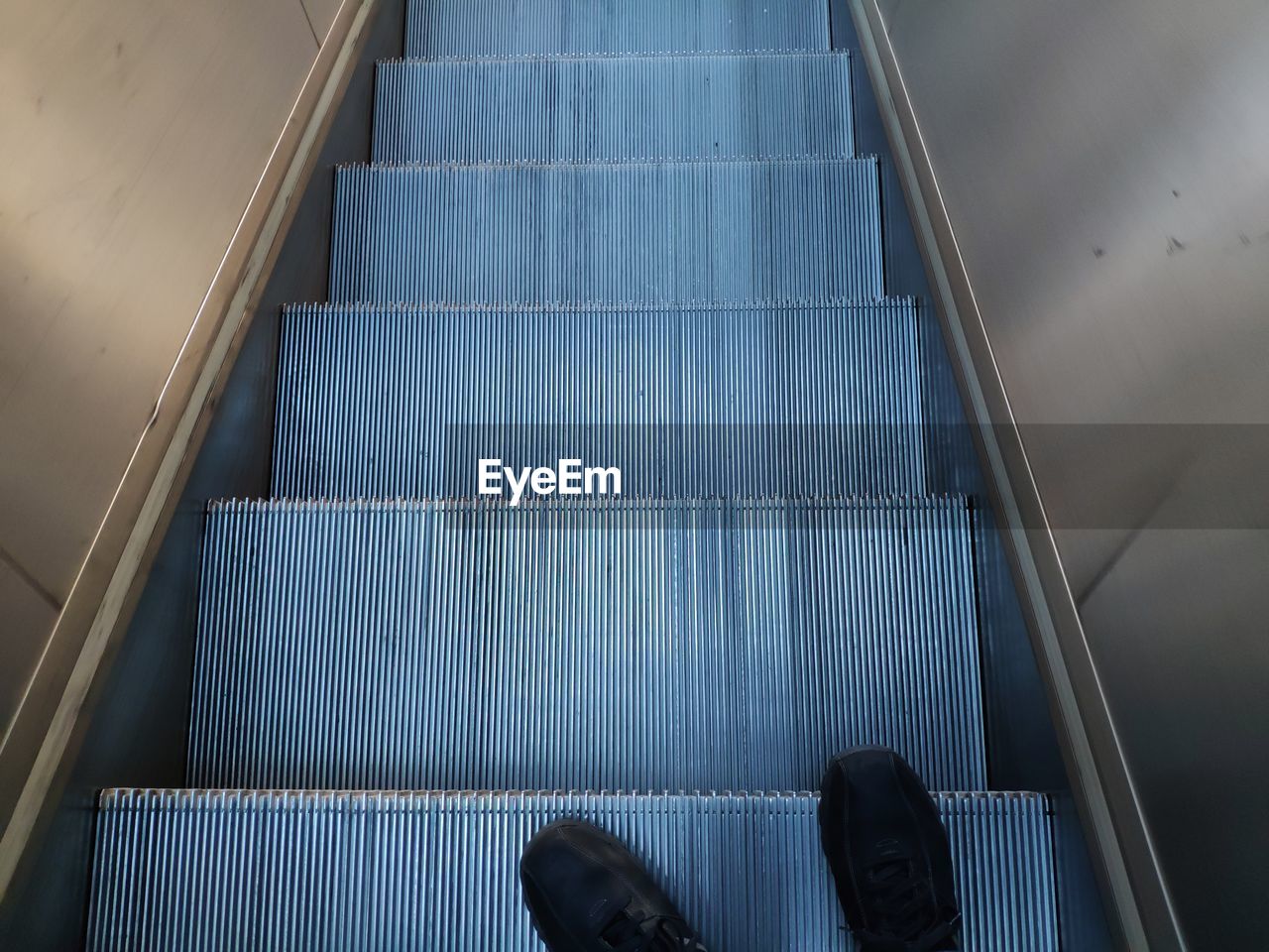 Low section of man standing on escalator