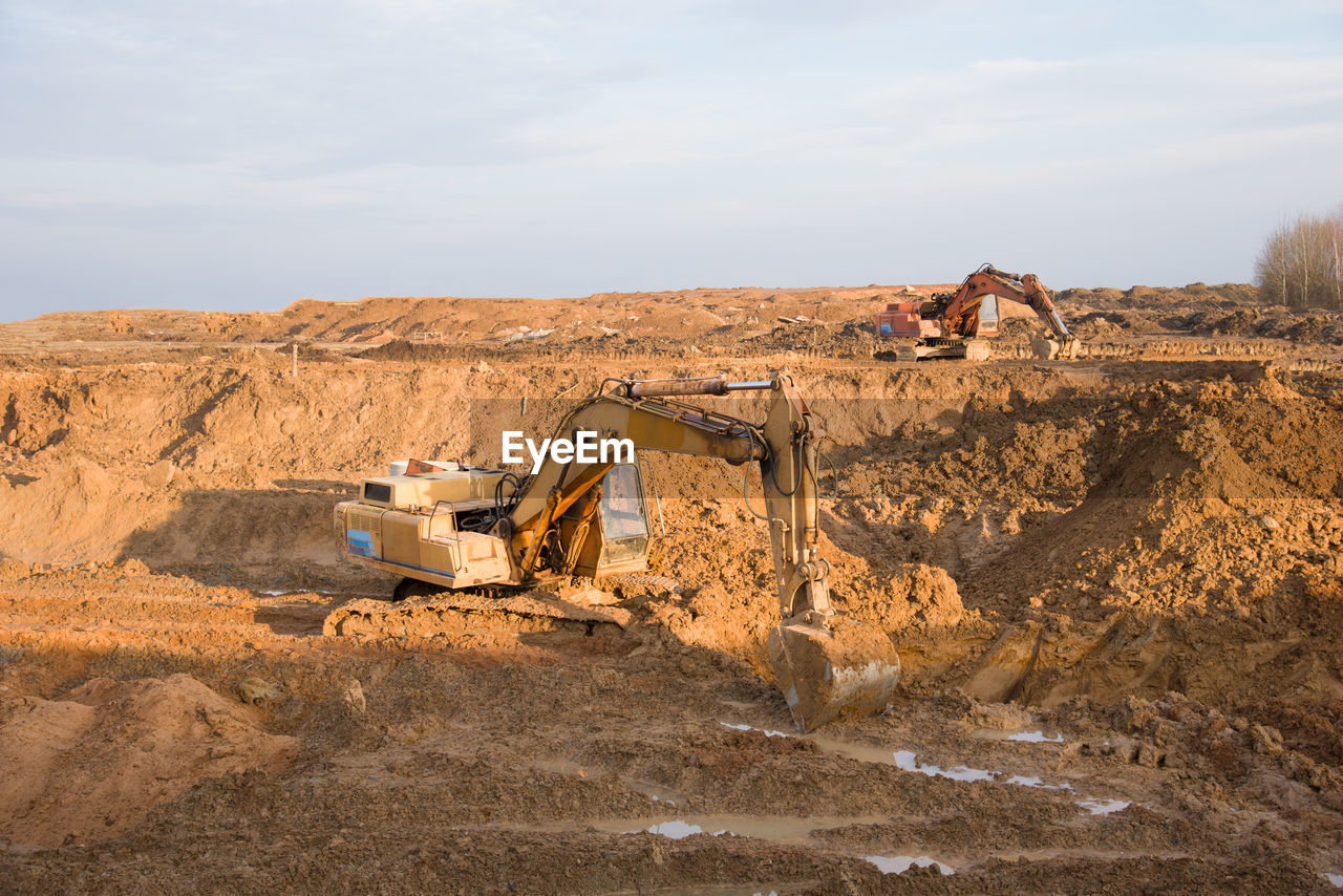 Excavators working at open-pit mining. backhoe during earthworks on sand quarry. earth-moving 