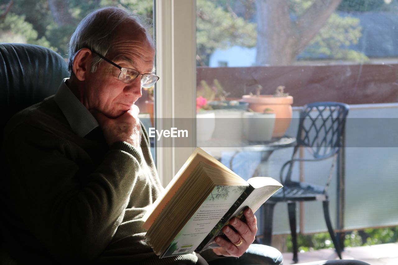 Elderly man reading book at home