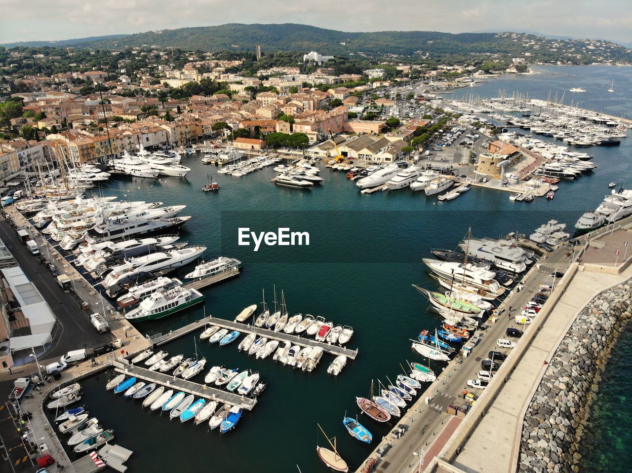 HIGH ANGLE VIEW OF BOATS MOORED AT HARBOR AGAINST BUILDINGS IN CITY