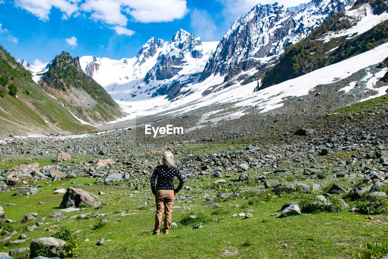 Full length of woman walking on field against snowcapped mountains