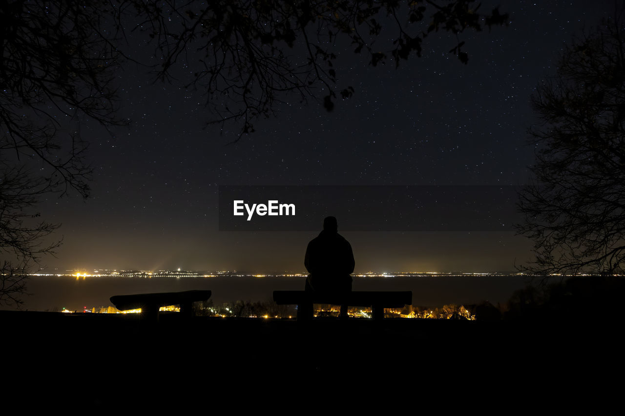 Starry sky at night over the lake balaton in hungary and man silhouette